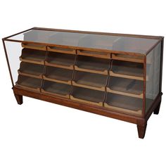 a wooden and glass display case with many compartments on the bottom, one section open