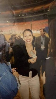 a woman standing in front of a group of people at a convention or event with her cell phone up to her ear