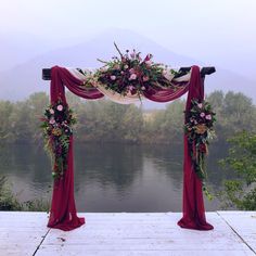 an outdoor wedding setup with flowers and draping on the top, overlooking a body of water