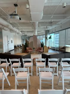 rows of white folding chairs in an office setting with large windows and floor to ceiling windows