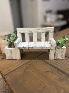 a miniature bench made out of wood with plants growing on it and two potted plants in the back