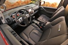 the interior of a red car with black leather seats and steering wheel, on display in a showroom