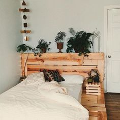 a bed made out of pallet wood with potted plants on the headboard