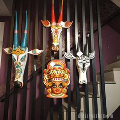 colorful masks are hanging on the wall in front of a stairwell railing with metal bars