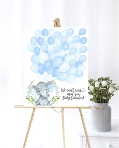 an easel with a baby elephant and blue balloons on it