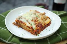 a white plate topped with lasagna covered in sauce and parmesan cheese