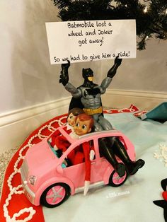 a birthday cake with batman and catwoman figures on the top, in front of a christmas tree