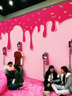 people sitting on the floor in front of a pink wall with sprinkles