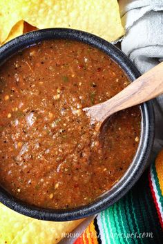 a black bowl filled with salsa and tortilla chips on top of a colorful table cloth