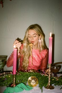 a woman sitting at a table with three candles in front of her and looking down