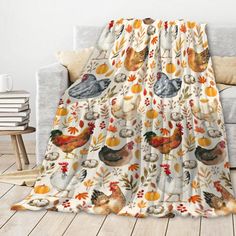 a couch covered in a blanket with chickens and pumpkins printed on the front, sitting next to a window