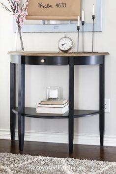 a table with a clock and some candles on it in front of a framed sign