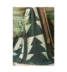 a green crocheted afghan with white stars on it, next to a pine tree