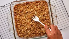 a person holding a fork over a casserole dish filled with oatmeal