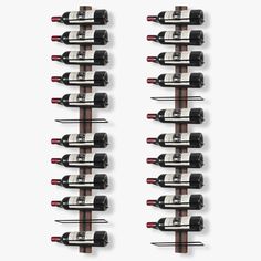 several bottles of wine are lined up in a row against a white wall with black handles