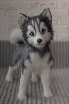 a stuffed husky dog sitting on top of a bed