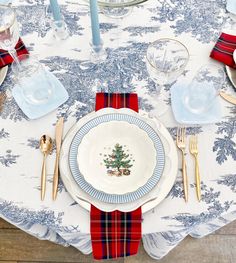 a christmas table setting with plates, silverware and plaid napkins on the table