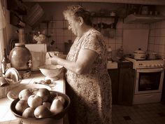 an older woman is preparing food in the kitchen with apples and pears on the counter