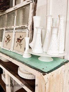 some white vases are sitting on a shelf in front of an old window frame