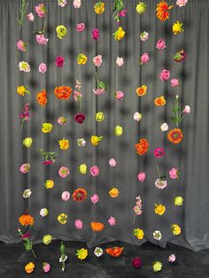 a curtain with flowers hanging from it's side in front of a gray background