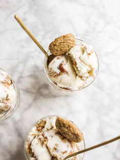 three desserts with ice cream and cookies in small glass dishes on a marble surface