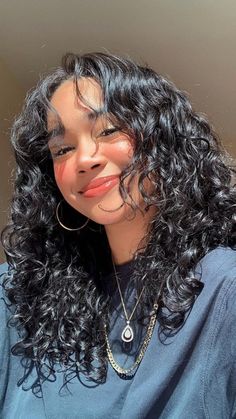 a close up of a person with long curly hair and wearing a blue shirt looking at the camera