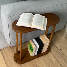 an open book sitting on top of a wooden table next to a gray couch in a living room