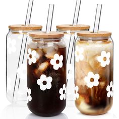 four mason jars with flowers painted on the lids and straws in each jar are lined up