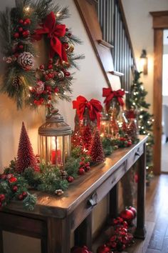 christmas decorations on a table in front of a stair case with candles and wreaths