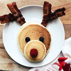 a plate topped with pancakes covered in bacon and a face made to look like a dog