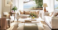 a living room filled with white furniture and lots of window sill curtains over the windows