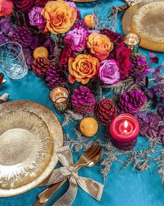 a table topped with plates covered in purple and orange flowers next to silver wares