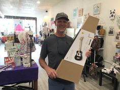 a man holding up a cardboard box with a pair of scissors on top of it