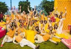 a group of people dressed in yellow and white posing for a photo together on the grass