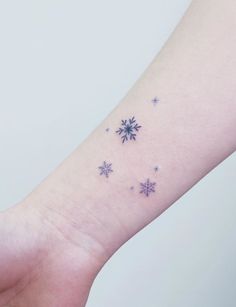 a small snowflake tattoo on the left inner arm and wrist, with stars all over it