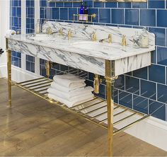 a bathroom with blue tiles and gold fixtures on the wall, along with a marble sink