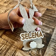 a hand holding a wooden sign that says selena