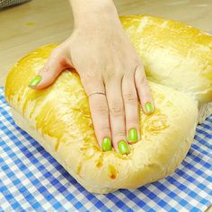 a woman's hand touching a piece of bread on top of a blue and white checkered table cloth