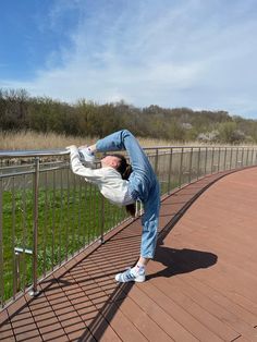 a person doing a handstand on a metal rail near a field and trees