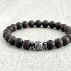 Men's beaded bracelet made with strong, stretchy cord and genuine/natural gemstones and wood. Features: ~ 6mm, 8mm or 10mm Ebony Blackwood beads ~ 6mm, 8mm or 10mm Map Jasper bead ~ 4mm, 6mm or 8mm Hematite rondelles ~ Strong, non-fraying elastic cord; simply slide bracelet on and off wrist ~ Comes packaged in a reusable microfibre pouch Please note that despite the name, the colour of this beautiful wood bracelet is actually a dark, rich brown. To ensure the perfect fit, please use the bracelet Wooden Beaded Bracelets, Slide Bracelet, Wood Bead Bracelet, Black Onyx Bracelet, Men's Bracelets, Wooden Bracelet, Wood Bracelet, Picasso Jasper, Bracelets Diy