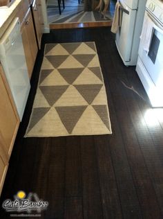 a kitchen with an area rug on the floor and white appliances in the back ground