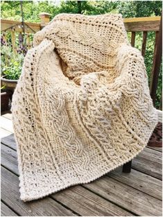 a crocheted blanket sitting on top of a wooden deck