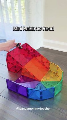 a rainbow colored object is on the floor in front of a person's hand