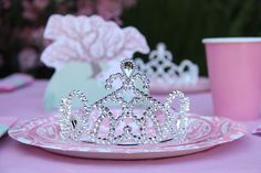 a tiara sitting on top of a pink plate next to a cup and saucer