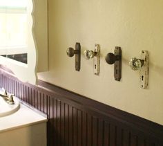 an old door knobs to hang towels on the wall next to a bathroom sink