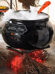 a large black pot filled with snow on top of a metal counter next to halloween decorations