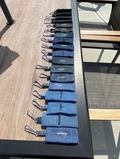 several pairs of blue jeans are lined up on a long table with chairs in the background