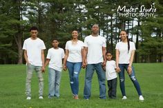 a family posing for a photo in the grass with trees in the backgroud