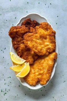 fried fish with lemon wedges on a white plate