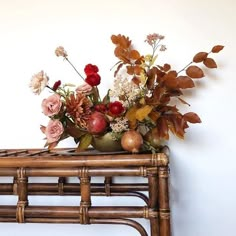 a vase filled with flowers sitting on top of a wooden table next to a wall